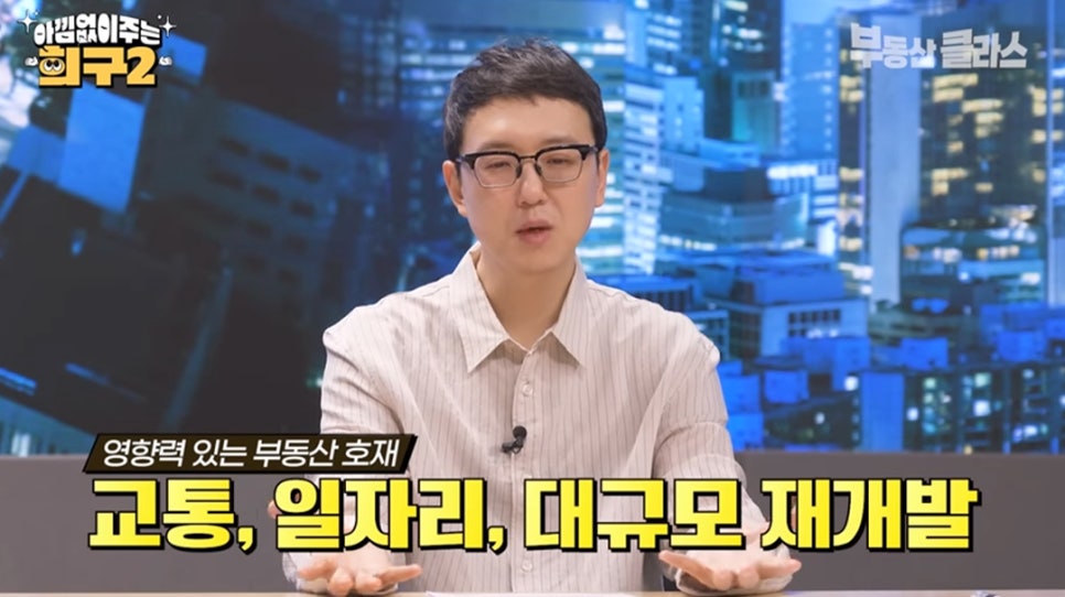 '송희구 작가가 정면을 향해 설명하는 모습'입니다. 화면 하단에는 검은색 띠 위에 '영향력 있는 부동산 호재'라고 적혀 있으며, 그 아래로 노란색 글씨의 '교통, 일자리, 대규모 재개발'이라는 자막이 크게 보입니다.