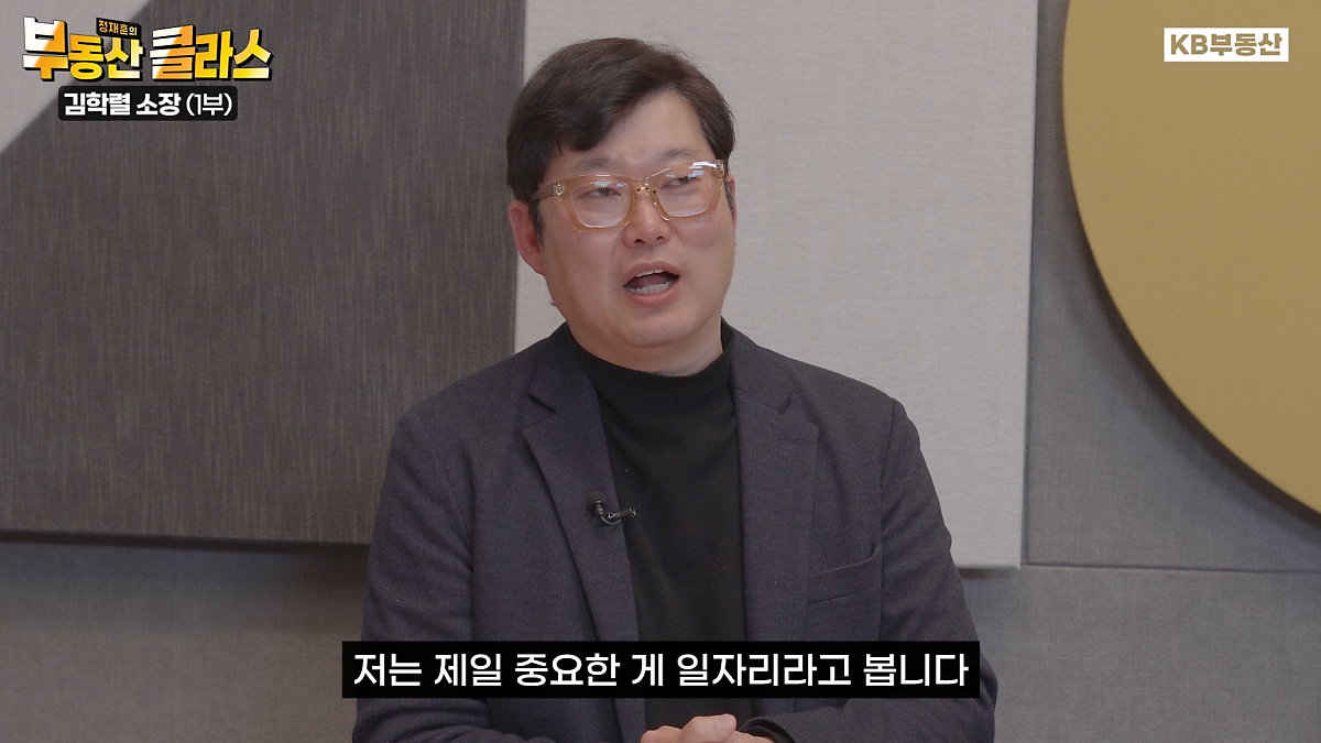 '김학렬 소장'이 말을 하고 있는 이미지. '검정' 양복을 입고 있다. '노란'배경이다.