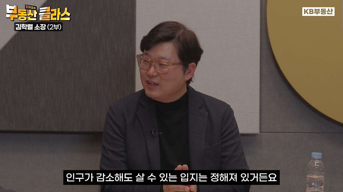 '김학렬 소장'이 말을 하고 있는 이미지. '검정' 양복을 입고 있다. '노란'배경이다. 인구가 감소해도 '입지'는 정해져있다고 얘기하고 있다.