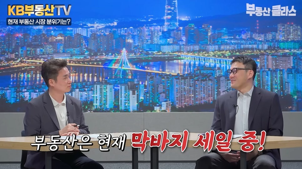 KB부동산 TV 방송 화면에서 두 출연자가 대담을 나누고 있습니다. 화면 하단에는 ‘부동산은 현재 막바지 세일 중!’이라는 붉은색 자막이 강조되어 있어, 현재 주택 매수 타이밍에 대한 전문가의 의견을 전달합니다.