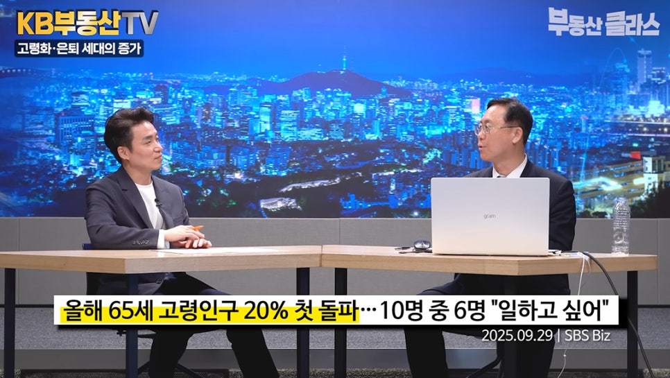 '두 명의 출연자가 대담을 나누는 스튜디오 전경'이다. 하단 뉴스 자막에는 '올해 65세 고령인구 20% 첫 돌파... 10명 중 6명 일하고 싶어'라는 인구 구조 변화에 관한 내용이 담겨 있다.