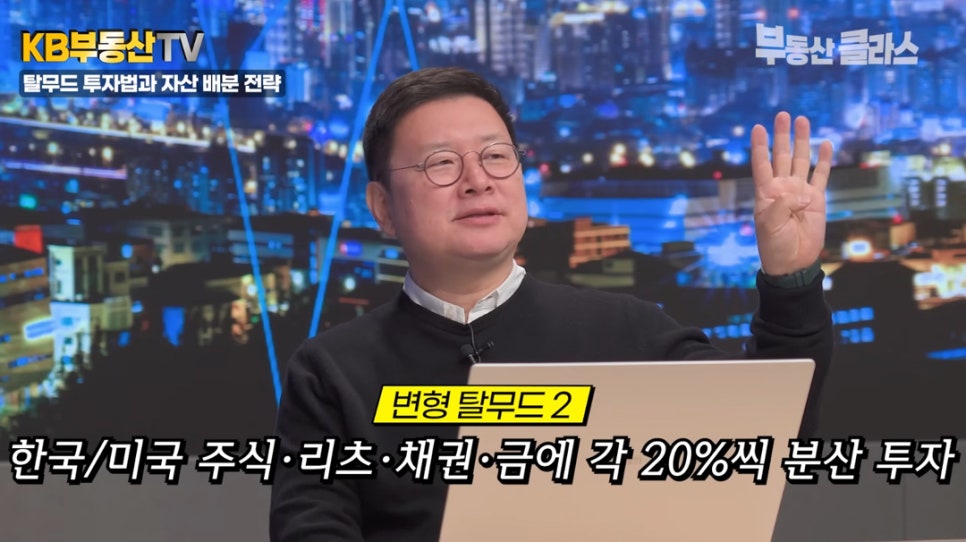 KB부동산TV '부동산 클래스'에서 홍춘욱 박사가 '변형 탈무드 2' 전략을 설명하는 모습입니다. 한국/미국 주식, 리츠, 채권, 금에 자산을 각 20%씩 분산 투자하라는 자막과 함께 손가락 4개를 펴며 강조하고 있습니다.