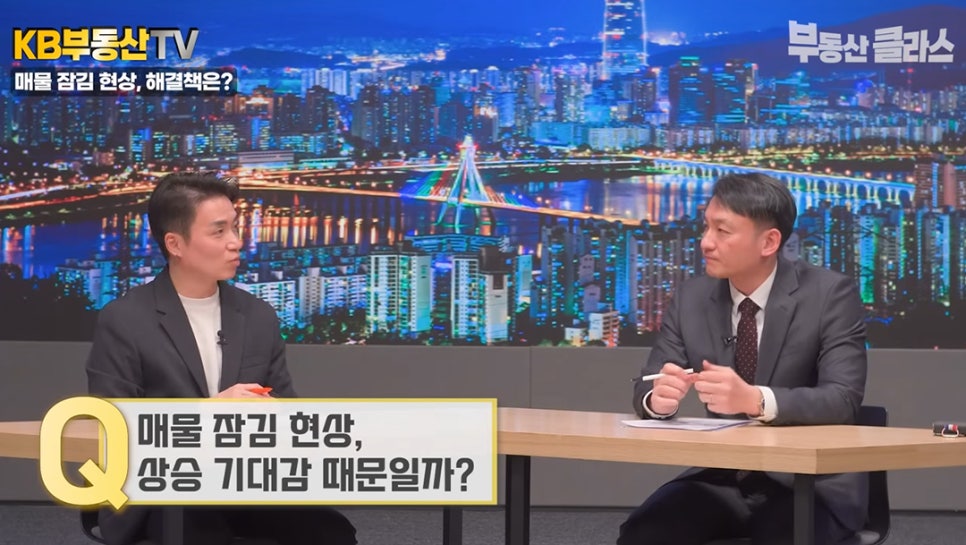 스튜디오에서 두 명의 출연진이 대담을 나누는 모습으로, 'Q. 매물 잠김 현상, 상승 기대감 때문일까?'라는 질문 자막이 하단에 크게 배치된 화면이다.