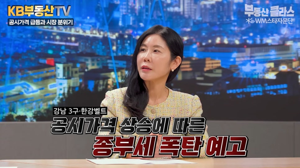 KB부동산 TV 방송 화면에서 '전문가가 설명하는 모습'이다. 하단 자막에는 강남 3구와 한강 벨트의 공시가격 상승에 따른 종합부동산세 폭탄이 예고된다는 내용이 담겨 있어 '세금 부담에 대한 주의를 환기'한다.