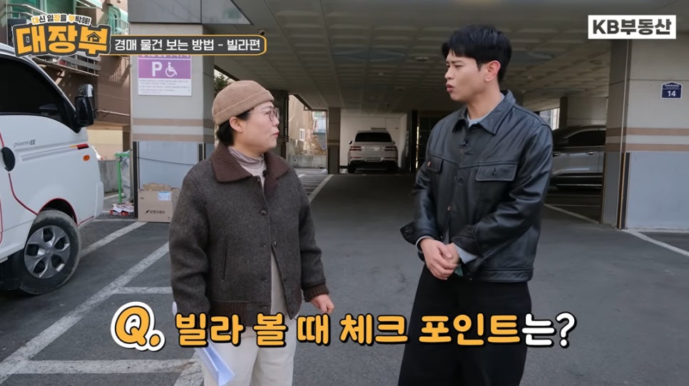 빌라 건물 주차장 앞에서 남녀 출연자가 '빌라 경매 시 현장에서 반드시 확인해야 할 체크포인트가 무엇인지 질문하는 장면'입니다.