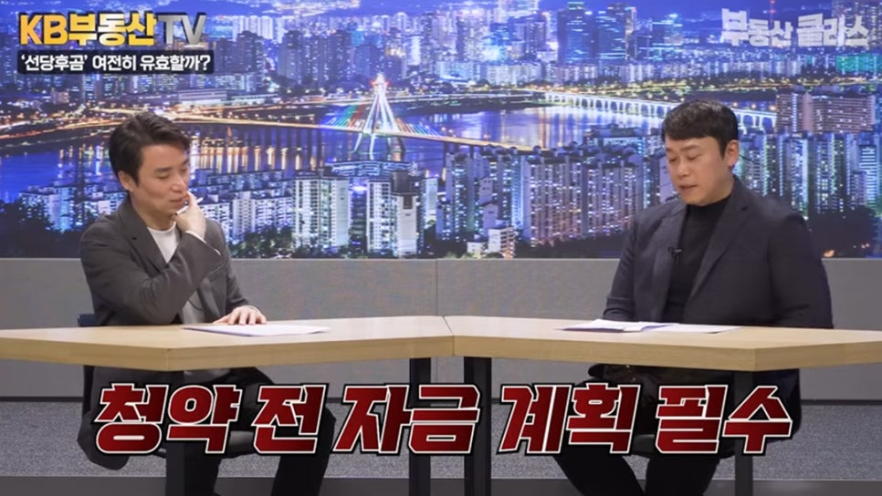 '두 명의 출연진이 대담을 나누는 전체 스튜디오 화면'입니다. 하단에는 붉은색 강조 자막으로 '청약 전 자금 계획 필수'라는 문구가 크게 적혀 있어 청약 시 자본 준비의 중요성을 강조합니다.