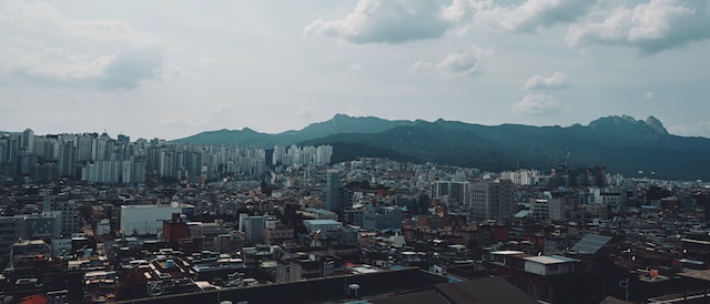 한 도시의 전경을 보여주고 있다. 아파트와 주택 등 다양한 건물이 세워져 있고, 멀리 있는 산지도 확인할 수 있다.