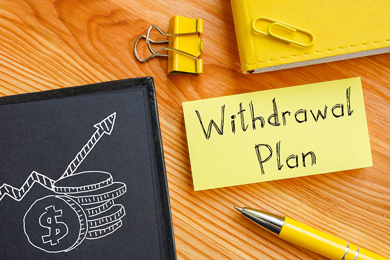 동전과 우상향 화살표 그림이 그려진 종이 옆에 'Withdrawal Plan(인출 계획)'이 적혀 있는 포스트잇이 붙어있다.