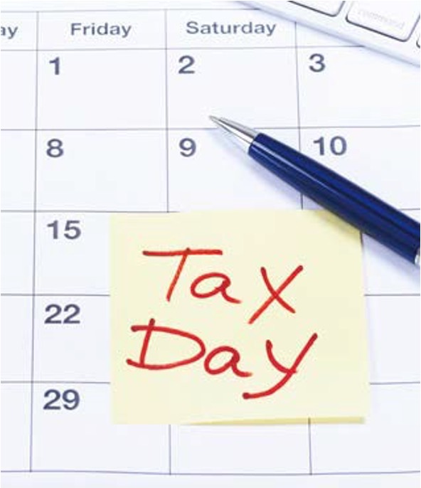 달력 위에 'Tax Day'라고 '붉은 글씨로 적힌 노란색 점착 메모지가 붙어 있고 그 옆에 파란색 볼펜이 놓여' 있다. 세금 신고 마감일이나 납부일을 잊지 않기 위해 표시해 둔 설정으로, 납세의 의무와 일정 관리의 중요성을 시각적으로 표현한다.