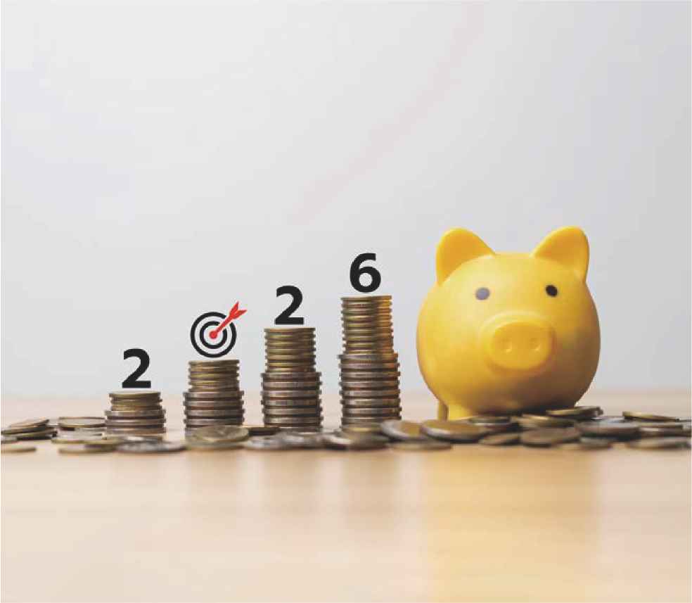 책상 위에 동전이 쌓여있는데 그 동전 위에 2026이라고 적혀있고, 옆에는 돼지 저금통이 있다.