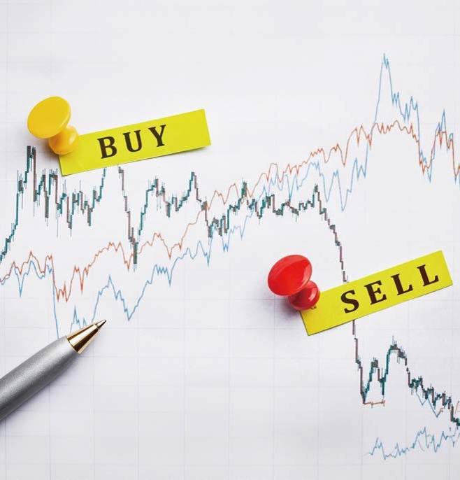 꺾은선 그래프 위에 'BUY'와 'SELL'이 적힌 노란색 메모지가 각각 노란색과 빨간색 핀으로 고정되어 있으며 옆에는 은색 펜이 놓여 있는 모습입니다.