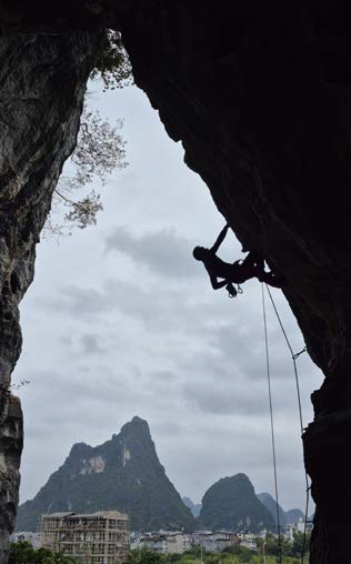 솟아 있는 카르스트 봉우리를 배경으로 '암벽'을 등반하는 사람의 실루엣이다.