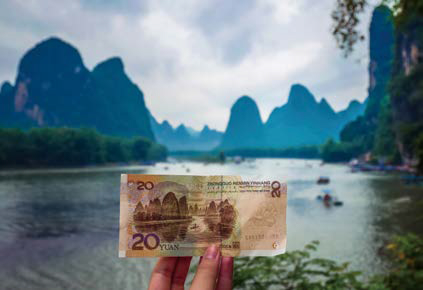 구이린의 상징인 카르스트 산수를 배경으로 '20위안 지폐'를 펼쳐 보이는 모습이다.