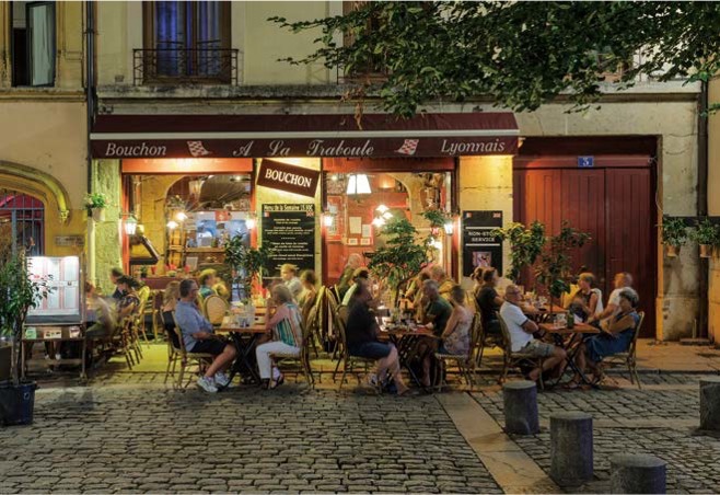 리옹의 전통 식당인 '부숑' 야외 테라스에서 여유로운 저녁 식사를 즐기는 사람들의 풍경이다.