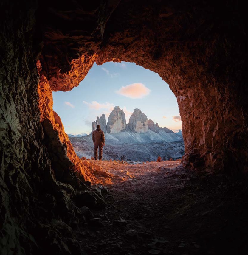'동굴 안쪽에서 밖을 내다본 시점으로, 돌로미티의 상징인 트레 치메 디 라바레도의 세 봉우리가 노을빛을 받아 신비롭고 웅장'하게 서 있다.