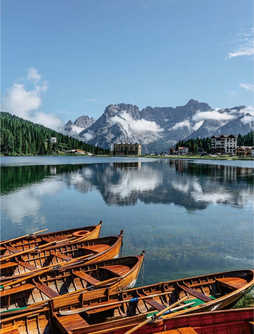 '잔잔한 미수리나 호수 위에 나무 보트들이 나란히 정박해 있으며, 맑은 호수면 위로 웅장한 소라피스 산맥과 주변 건물들이 거울처럼 반사'되어 있다.