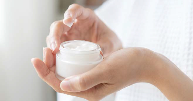 손에 흰색 '보습 크림'이 담긴 유리 용기를 들고 있는 모습이다.