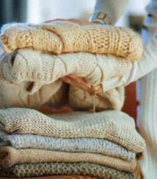 뮤트 톤의 니트들이 잘 접혀져 차곡차곡 쌓여있는데 여자의 손이 그중 2개의 니트를 집어 들었다.