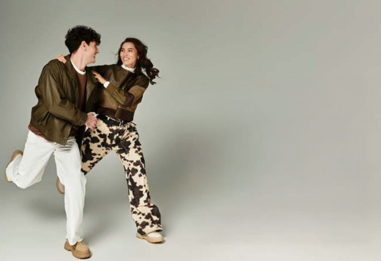 남녀 두 명의 모델이 활동하기 편한 옷을 입고 달리는 듯한 포즈를 취하며 서로를 보고 웃고 있다.