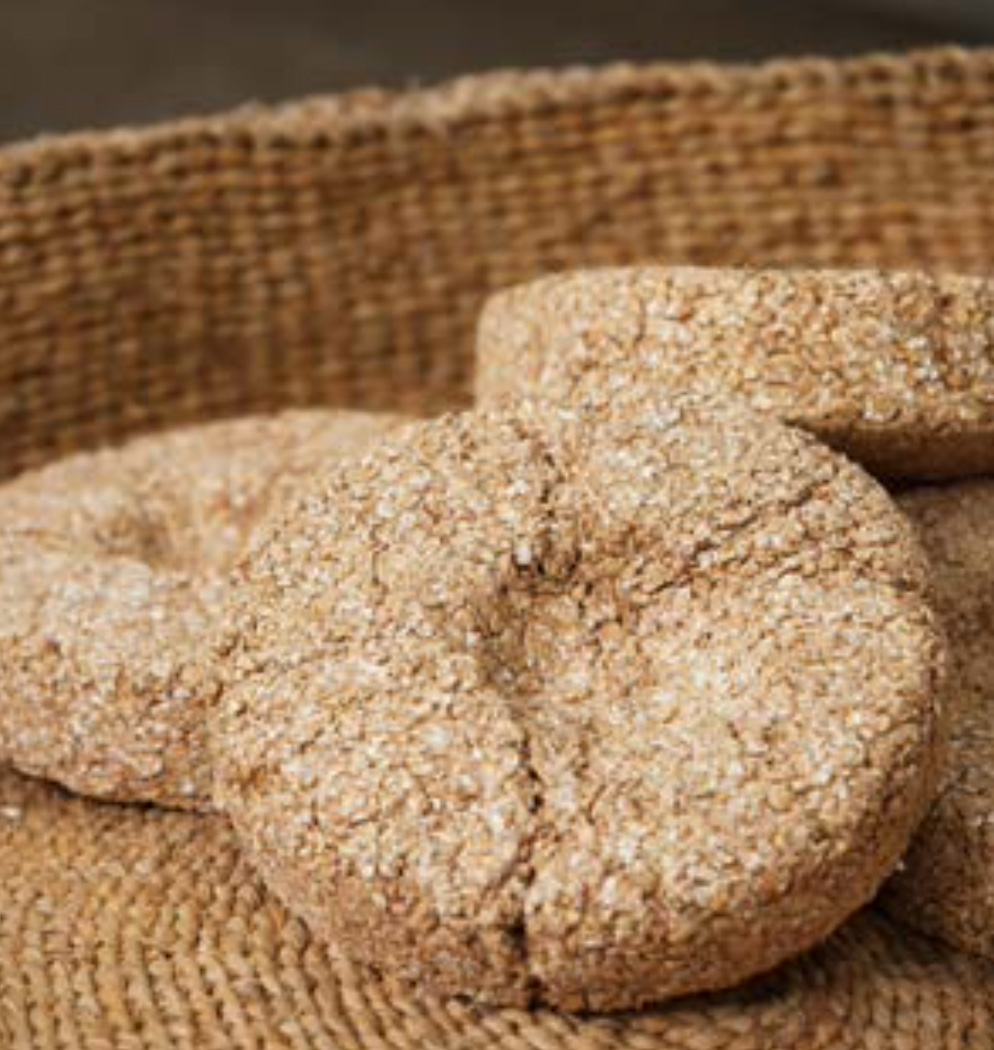 짚으로 엮은 바구니 안에 거친 '질감이 살아있는 동그랗고 도톰한 모양의 전통 누룩'들이 담겨 있는 모습입니다.