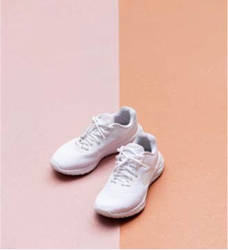 '파스텔 톤 배경 위에 깔끔하게 놓인 흰색 운동화 한 켤레가 정돈된 모습'이다.