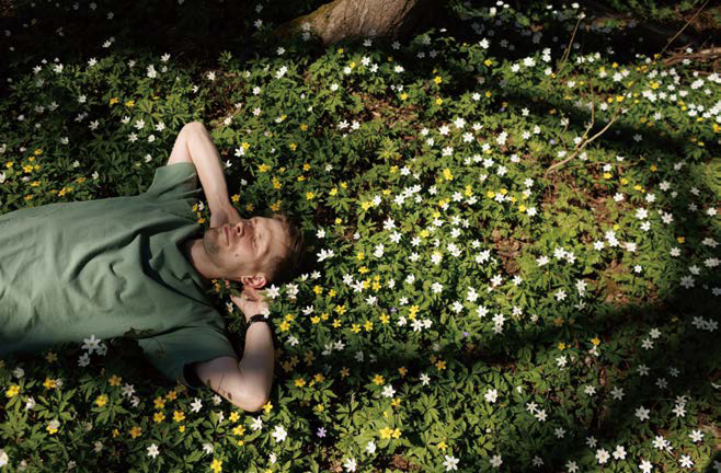풀과 꽃이 핀 들판에서 '낮잠'을 자고 있는 남성의 모습이다.