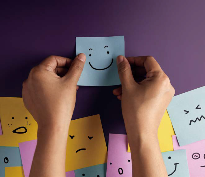 '웃고 있는 표정'이 그려진 파란색 포스트잇을 붙이고 있다. 밑에는 다양한 표정의 포스트잇이 여러장 붙여있다.