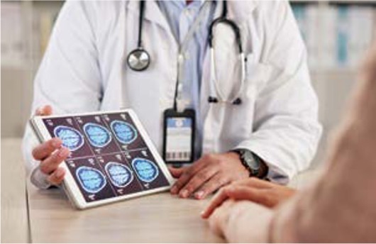 '의사가 태블릿 PC에 띄워진 뇌 스캔 영상들을 환자에게 보여주며' 현재 상태에 대해 상담을 진행하고 있다.