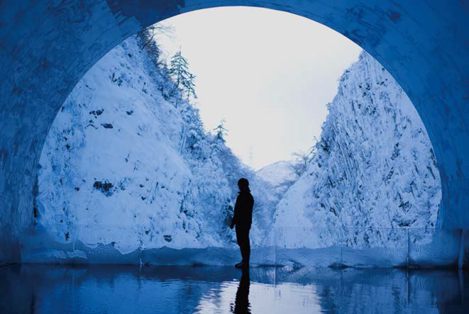 터널 앞에서 눈 덮인 풍경을 바라보는 '사람의 실루엣'이 보이는 모습이다.