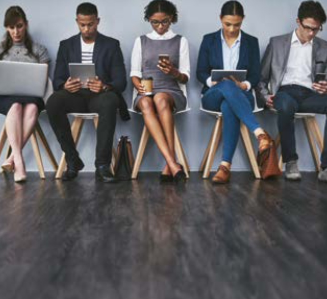 의자에 나란히 앉은 다양한 성별, 인종의 직장인들이 '노트북·태블릿·스마트폰을 보며 대기하는 모습'이다.