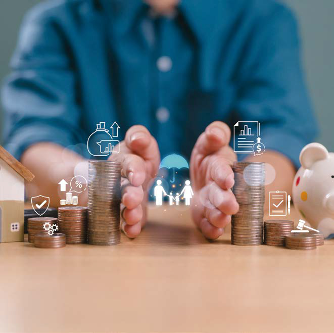 책상 위에 쌓인 동전 더미를 두 손으로 감싸 보호하는 사람의 모습. 왼쪽에는 미니어처 집과 금융 관련 아이콘(이자율, 성장 그래프, 보안 등), 오른쪽에는 돼지 저금통과 재무 문서 아이콘이 함께 보이며, 중앙에는 가족을 상징하는 아이콘이 표시되어 있어 자산 보호와 재무 관리를 시각적으로 표현하고 있다.