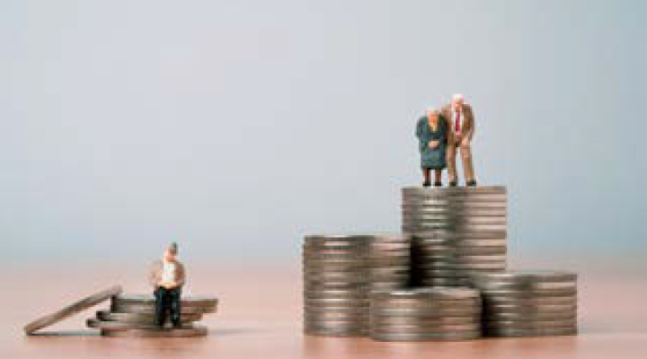 원목 책상 위에 동전들이 각자 다른 높낮이로 쌓여있고 왼쪽엔 혼자 앉아있는 노인 모형과 오른쪽엔 남녀 두 명의 노인 모형이 서있다.