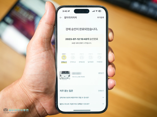왼손으로 스마트폰을 들고 'KB차차차' 앱 내 '팔아춰차차차' 기능을 활용.  정면, 후면, 계기판 사진 등록 후 '경매 승인' 완료 단계를 보여주는 이미지.