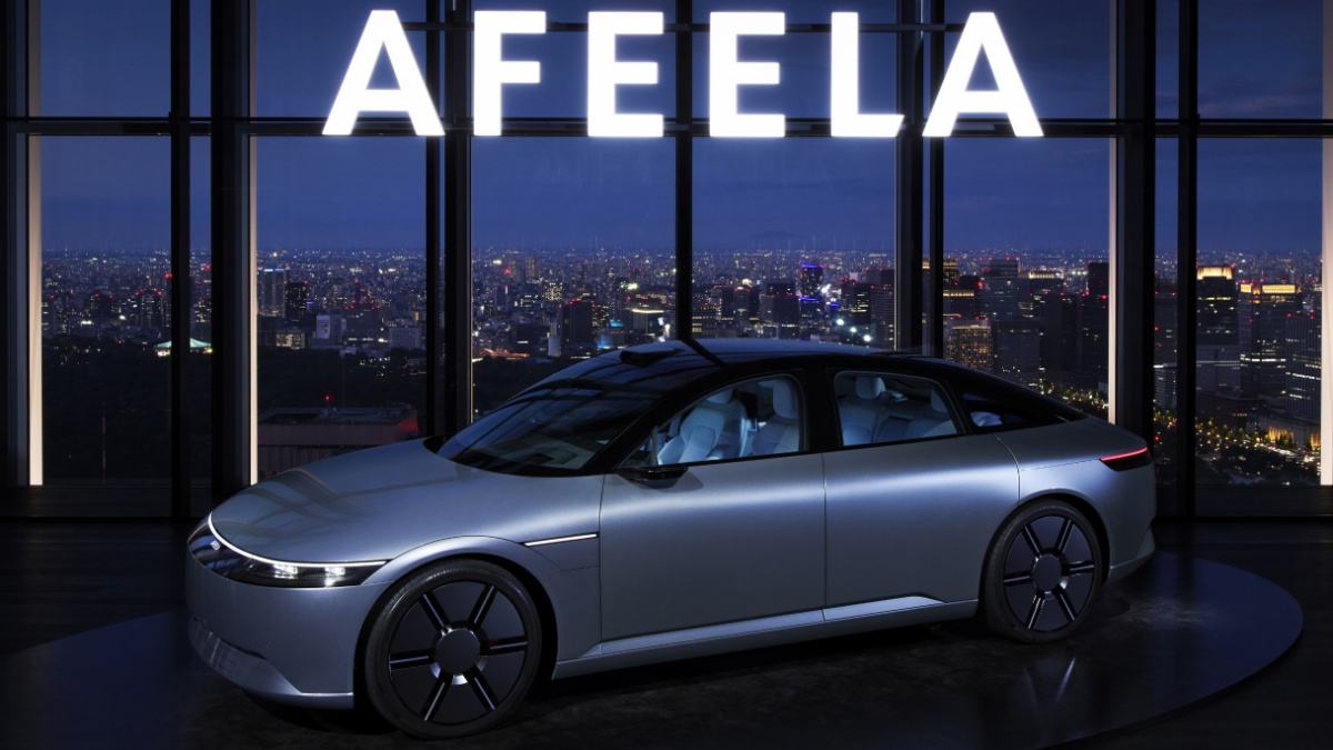 아피라 1 측면이 보이게 세워져 있고, 그 위에는 'AFEELA' 단어로 된 조명이 빛나고 있다.