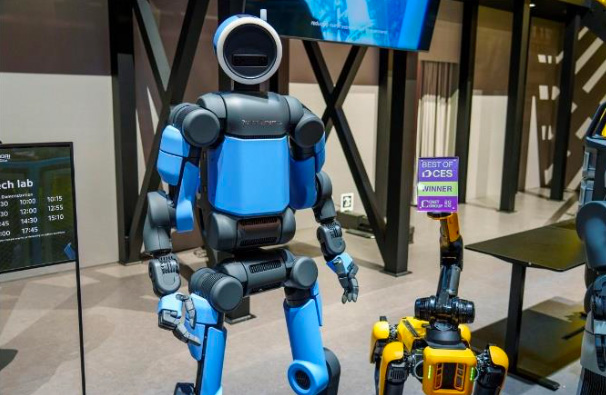 전시장에 세워진 보스턴다이내믹스의 휴머노이드 로봇 '아틀라스'와 4족 보행 로봇 '스팟'의 모습입니다. 파란색 본체의 아틀라스가 정면을 응시하며 서 있는 장면을 담고 있습니다.