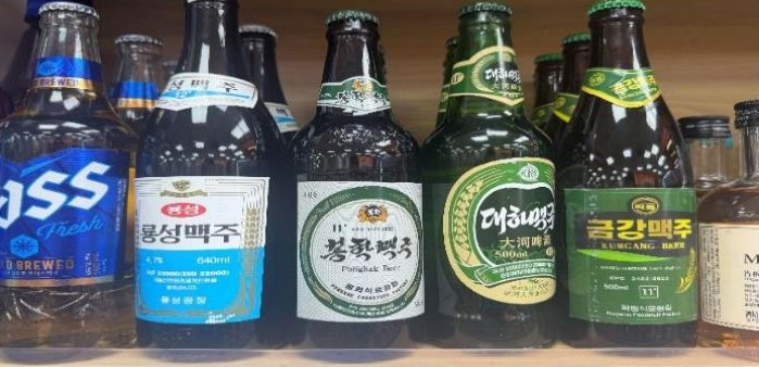 '제3국 상점에서 판매 중인 남한과 북한 맥주를 함께 촬영한 사진'으로, 북한산 맥주가 해외 유통망에 진출해 다양한 브랜드와 함께 판매되는 현황을 보여주는 이미지다.