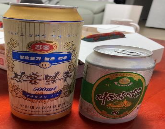 '2019년에 구매한 경흥맥주와 대동강맥주 캔 제품을 함께 촬영한 사진'으로, 북한 캔맥주의 디자인과 포장 형태를 비교하며 당시 생산 제품의 특징을 보여주는 이미지다.