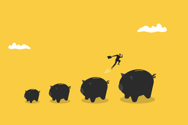 가방을 든 남자가 점점 커지는 저금통 위를 뛰어가고 있다.