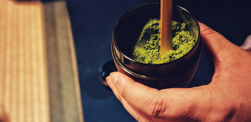 플라스틱 통에 담긴 말차 가루를 휘젓고 있다.