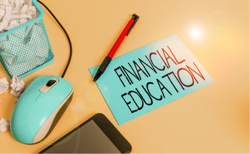  노란색 책상 위에 'financial education'(금융교육)이라고 적힌 민트색 카드가 놓여 있고, 주변에 컴퓨터 마우스, 펜, 스마트폰, 구겨진 종이가 담긴 연필꽂이가 있다. 무료 금융교육, 경제교육을 제공하는 KB 머니스페이스 아카데미를 상징한다.
