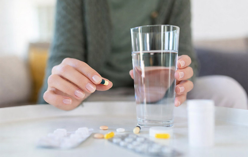 한 손엔 영양제, 한 손엔 물이 담긴 유리잔을 잡은 손의 모습이다. 영양제 먹는 시간 내용을 보조한다.