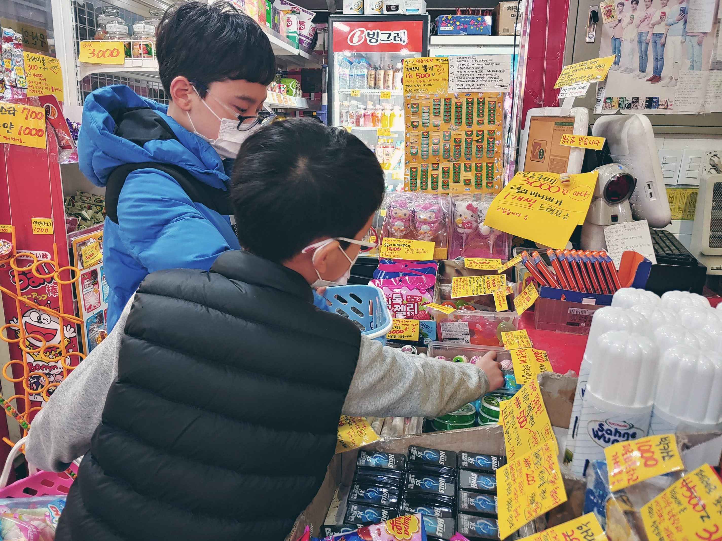 남자 아이 2명이 마트에서 물건을 고르고 있다.