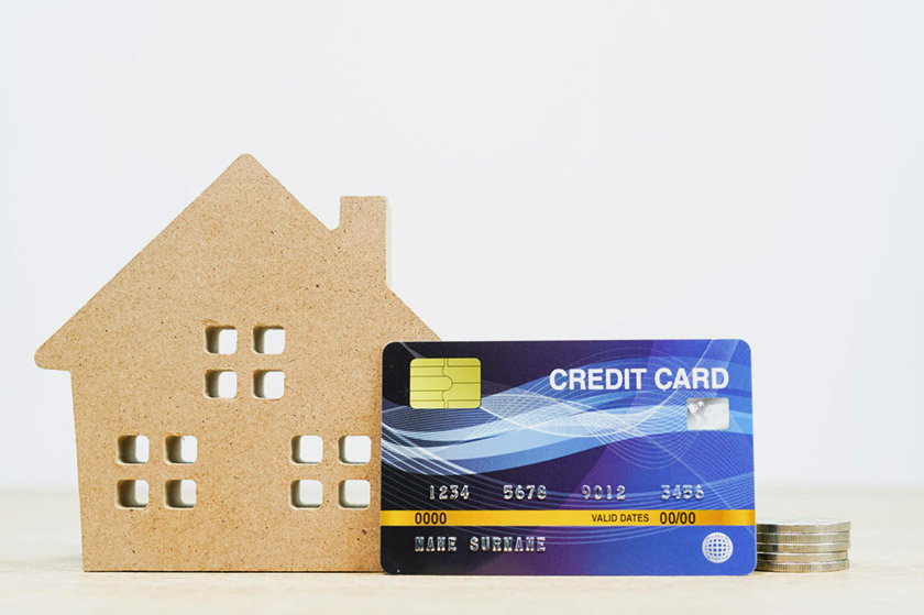주택 나무모형 옆에 신용카드와 동전이 놓여 있다.