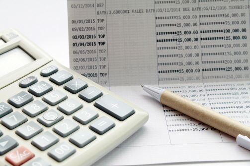 통장 옆에 펜과 계산기가 놓여 있다.