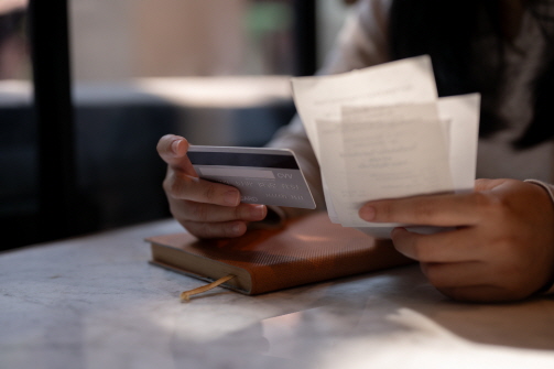 한 손에는 카드, 한 손에는 영수증을 보면서 결제 내역을 비교하고 있다.