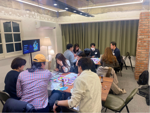 테이블이 4명씩 앉아 캐시플로우 보드게임을 하면서 경제 공부를 하는 사진